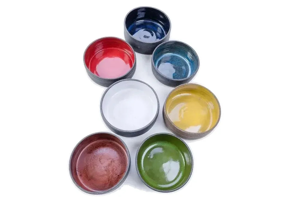 Seven glaze colors of the 14 oz ceramic vessel arranged in a loose circle from above