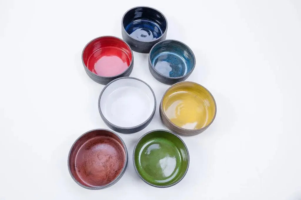 Seven glaze colors of the 14 oz ceramic vessel arranged in a loose circle from above