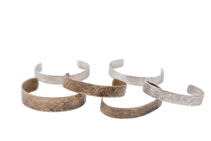 Hammered cuff bracelets in silver and copper arranged in a loose cluster