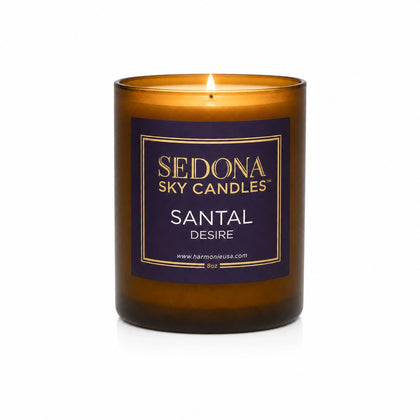 Santal Desire Candle in Sedona Sky amber glass, 8 oz, lit with a glowing flame on a white background