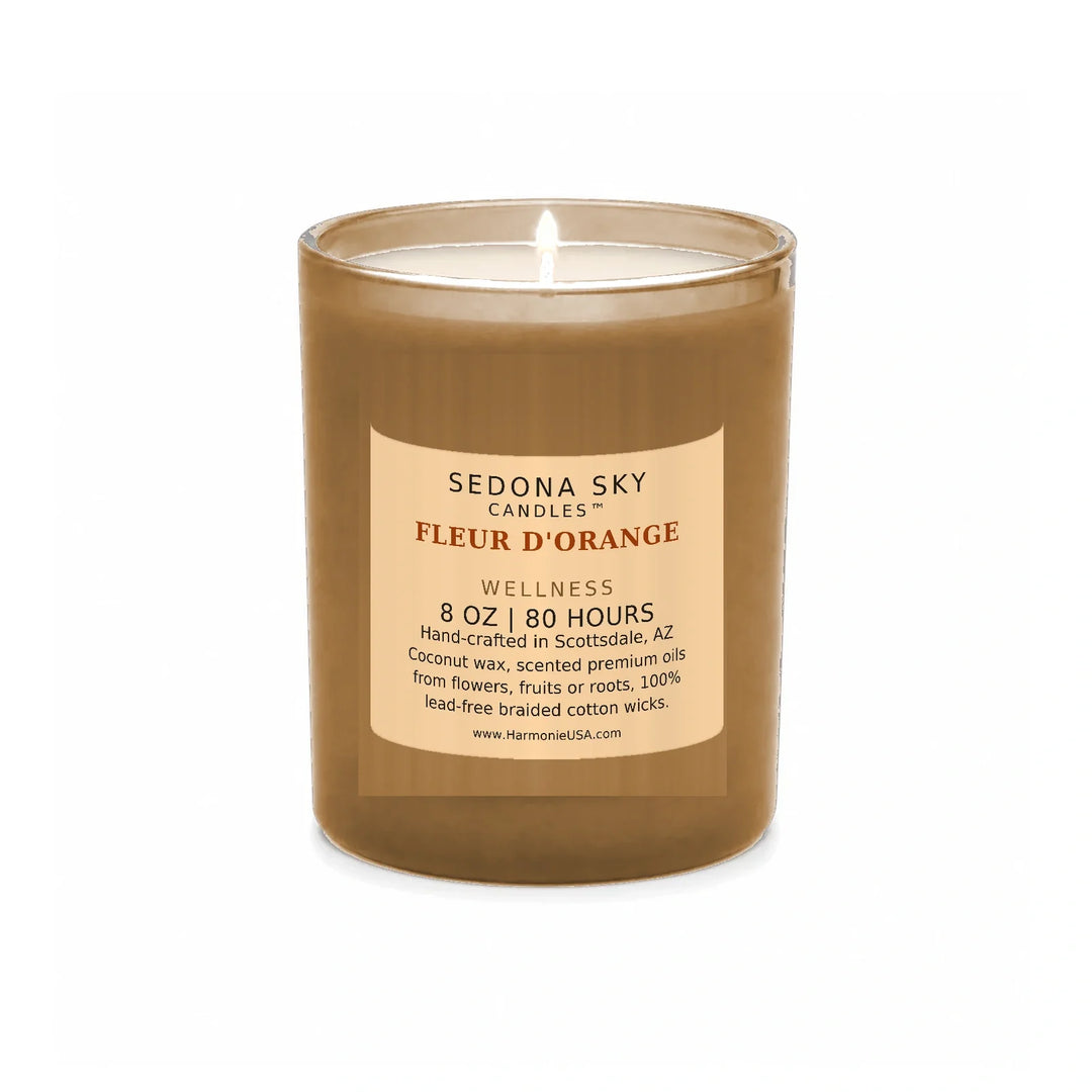 Sedona Sky Fleur d'Orange candle, 8 oz frosted coral glass jar with matte apricot label, lit wick and visible wax pool, on a seamless white background