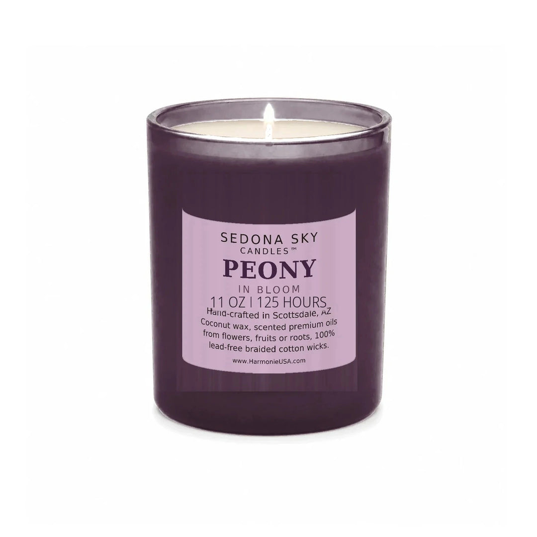 Sedona Sky Peony In Bloom candle, 11 oz plum glass jar with matte plum label, lit wick and visible wax pool, on a seamless white background