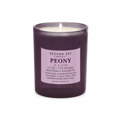 Sedona Sky Peony In Bloom candle, 11 oz plum glass jar with matte plum label, lit wick and visible wax pool, on a seamless white background