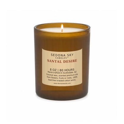 Sedona Sky Santal Desire candle, 8 oz amber glass jar with matte Amber Sand label, lit wick and visible wax pool, on a seamless white background