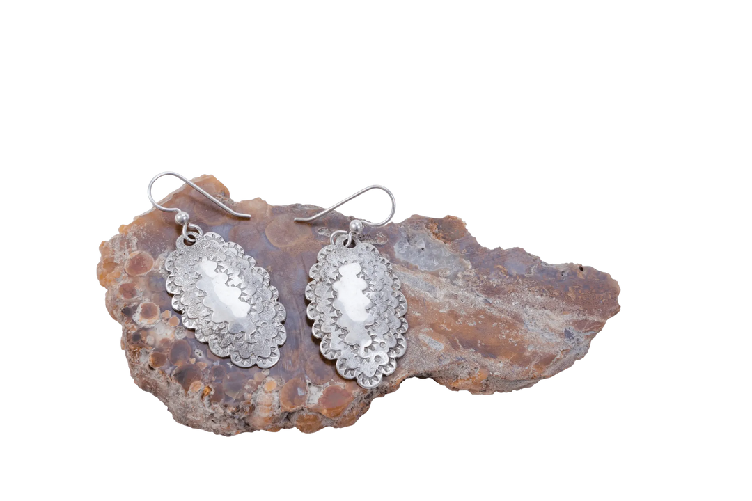 Close view of hammered Roosevelt dime earrings on agate showing the coin's scalloped edge