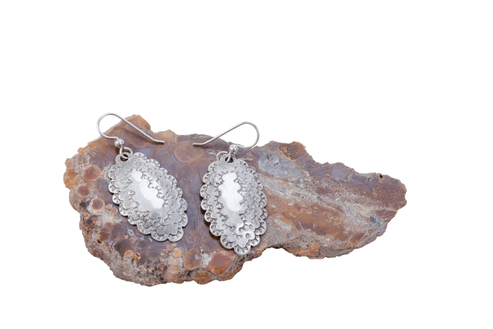 Close view of hammered Roosevelt dime earrings on agate showing the coin's scalloped edge