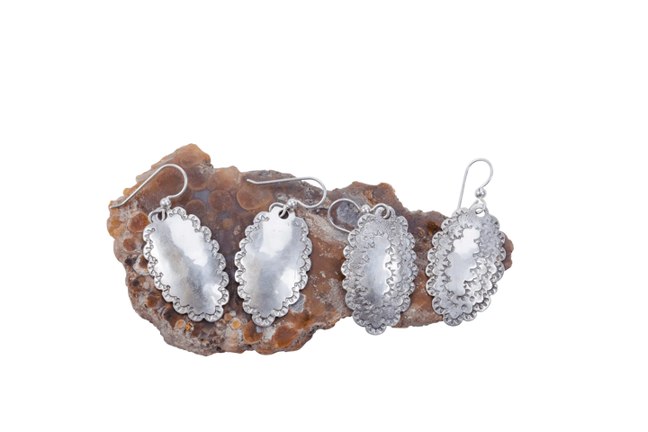 Two pairs of hammered Roosevelt dime earrings resting on a piece of raw agate