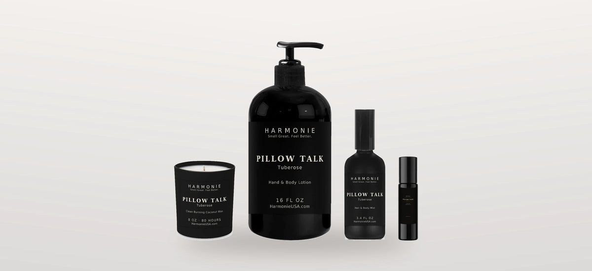 Harmonie Pillow Talk Tuberose ensemble — 8 oz candle, 16 oz hand and body lotion, 3.4 oz hair and body mist and perfume roller on a soft studio background
